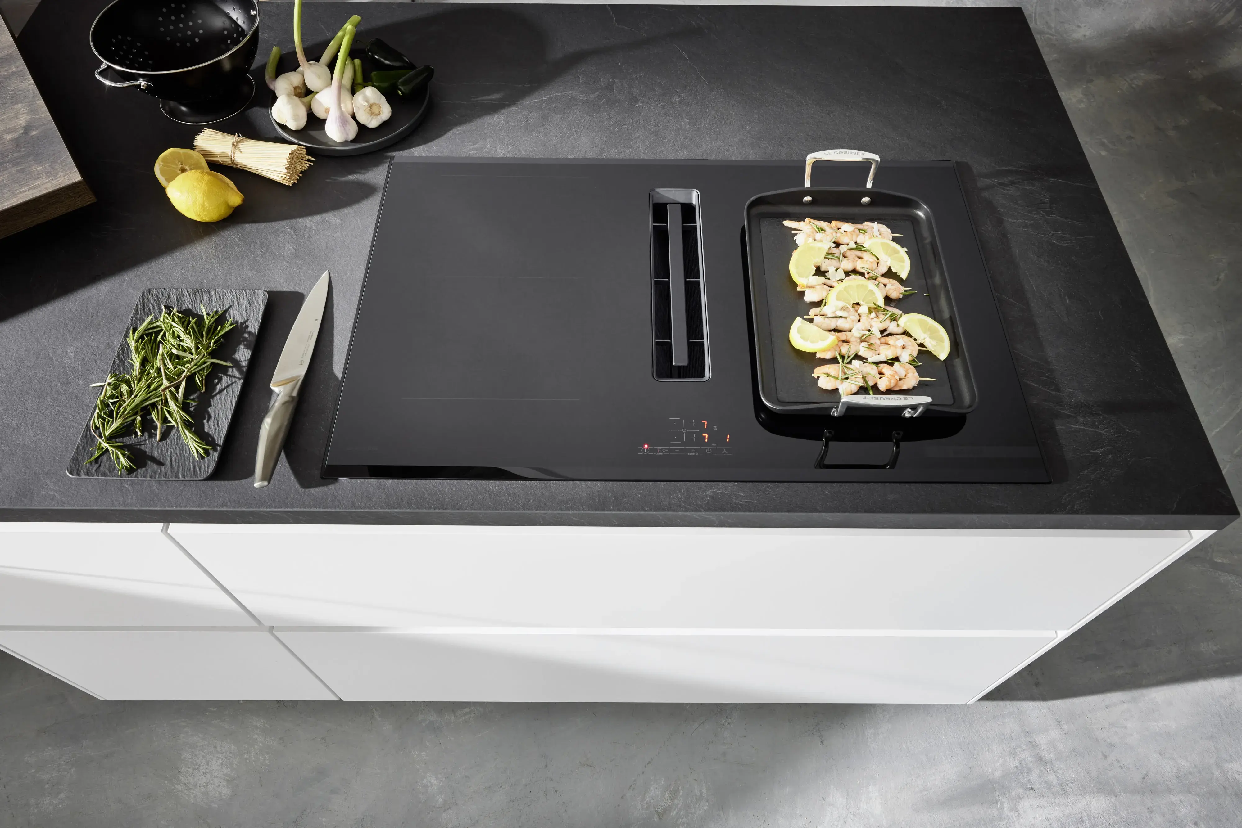 Schwarzweiße Kochinsel weiße grifflose Fronten APL Schiefer-Optik mattschwarzes Kochfeld mit Muldenlüfter